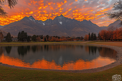 Lake Reflecting Fiery Sunset Over Mountains