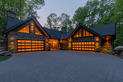 Stone House with Illuminated Garages at Dusk
